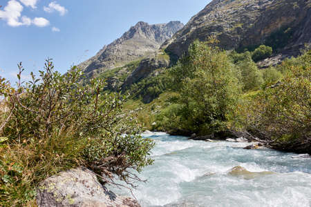 Mountain river water landscape. Alps. The cloudy sky in clear sunny day. Warm summer. Time for pedestrian tourism and family holiday with friends. Clear. Color.の写真素材