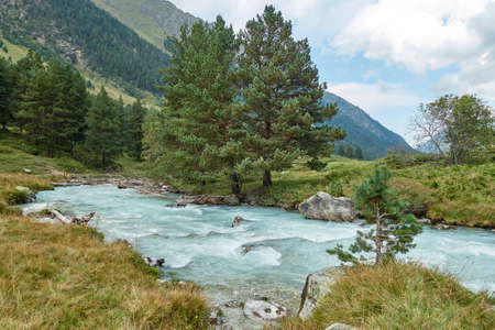 Mountain river water landscape. Alps. The cloudy sky in clear sunny day. Warm summer. Time for pedestrian tourism and family holiday with friends. Beautiful view.の写真素材