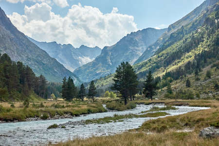Mountain river water landscape. Alps. The cloudy sky in clear sunny day. Warm summer. Time for pedestrian tourism and family holiday with friends. Outdoor. Green wood.の写真素材