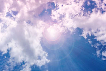 A bright ray of sunshine breaks through the fluffy white clouds. The mysterious light of day. mystery; background; weatherの写真素材