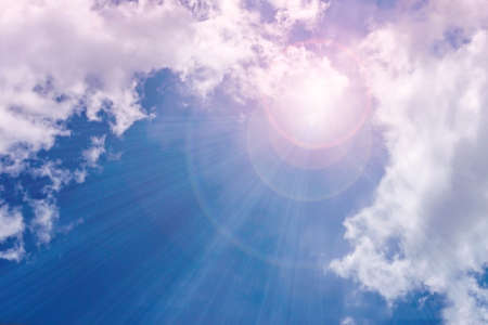 A bright ray of sunshine breaks through the fluffy white clouds. The mysterious light of day. nature; heaven; naturalの写真素材