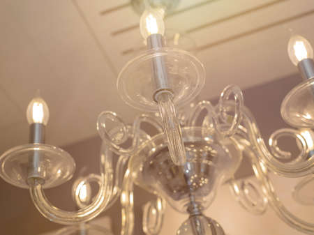 Close up on crystal of classic style chandelier, is a branched ornamental light fixture designed to be mounted on ceilings. Soft warm filter, selective focus. Transparent glass.の写真素材