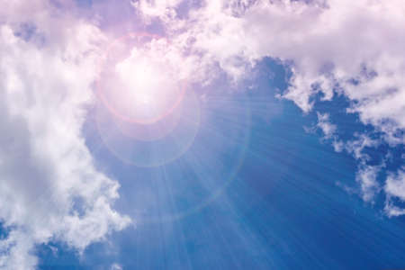 A bright ray of sunshine breaks through the fluffy white clouds. The mysterious light of day.
