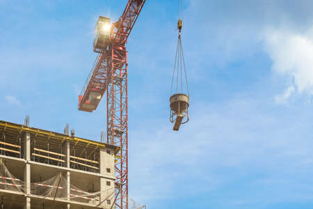 One high-rise red crane with flare against a house and sky during the construction phase. Industry concept for low-income young families. Mortgage, business, real estate loan.の写真素材