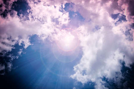 A bright ray of sunshine breaks through the fluffy white clouds.の写真素材