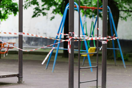 The play park of amusement and sports for young children is wrapped in red barrier tape. Prohibition...