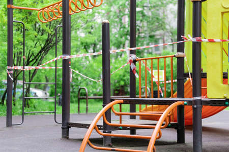 The play park of amusement for young children is wrapped in red barrier tape. Outside. Prohibition...
