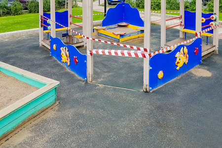 A children's sandpit on the playground wrapped with red barrier tape. Prohibition of outdoor walks,...