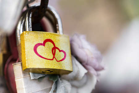 Hinged metal lock golden color c painted two red hearts. The concept of a couple in love, relationships, marriage, wedding. Outdoors. Close up.の写真素材