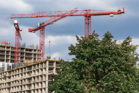Several red cranes have been put to work on the construction of a modern multi-storey residential complex. Concept work for people with the profession of builder.の写真素材