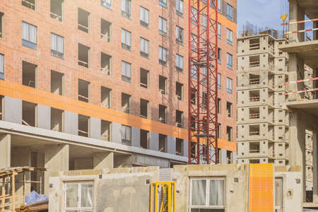 The part of red crane against a house during the construction phase. Industry concept for low-income...