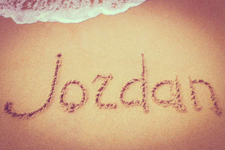 Jordan title on the sand beach of the coast Red sea. Surf. The pink vignette in the photo.