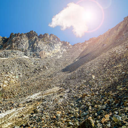 A picturesque mountain landscape with a single cumulus cloud. Daytime. Sun optimistic Glare.の写真素材