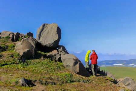 Two teenage boys in a yellow and red jacket stand back on the mountain and talk to each other. Friends went on a picnic trip. scenic mountain scenery. A clear summer windy day.の写真素材