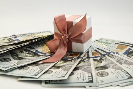 white present box with pink ribbon on the american dollars background, cash and presents, holiday...