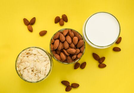almond nuts in the glass and almond chips and almond milk in the glass on the white and yellow background, copy space, Making almond milk from dried almondsの写真素材