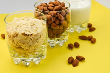 almond nuts in the glass and almond chips and almond milk in the glass on the white and yellow background, copy space, Making almond milk from dried almondsの写真素材