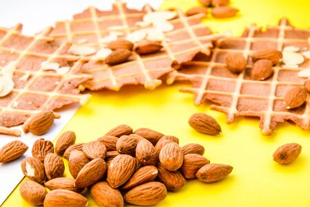 homemade waffles with almond nuts and almond flakes on the white and yellow background, copy spaceの写真素材