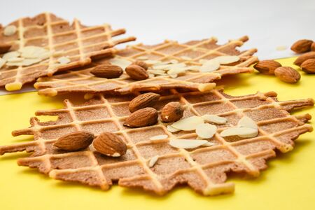 homemade waffles with almond nuts and almond flakes on the white and yellow background, copy spaceの写真素材
