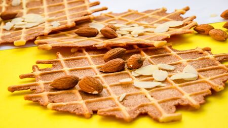 homemade waffles with almond nuts and almond flakes on the white and yellow background, copy spaceの写真素材