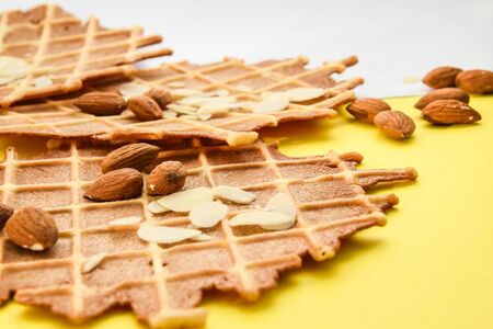 homemade waffles with almond nuts and almond flakes on the white and yellow background, copy spaceの写真素材