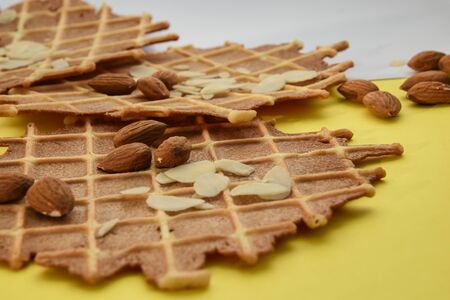 homemade waffles with almond nuts and almond flakes on the white and yellow background, copy spaceの写真素材