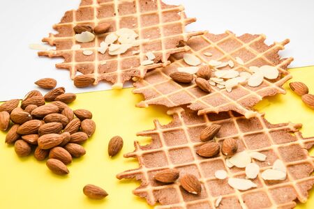 homemade waffles with almond nuts and almond flakes on the white and yellow background, copy spaceの写真素材