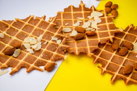 homemade waffles with almond nuts and almond flakes on the white and yellow background, copy spaceの写真素材