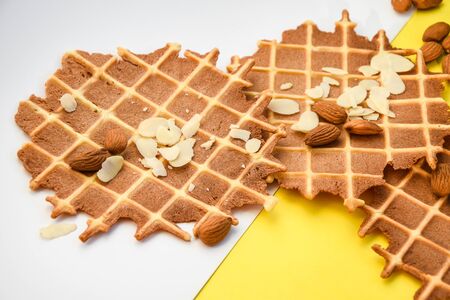 homemade waffles with almond nuts and almond flakes on the white and yellow background, copy spaceの写真素材