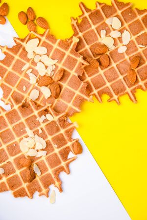 homemade waffles with almond nuts and almond flakes on the white and yellow background, copy spaceの写真素材
