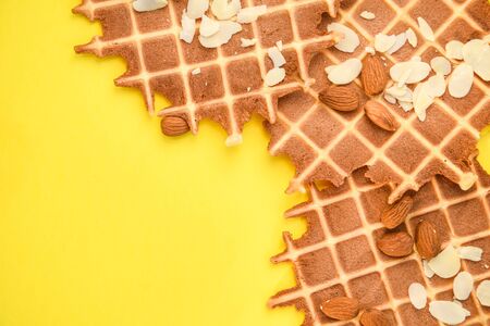 homemade waffles with almond nuts and almond flakes on the white and yellow background, copy spaceの写真素材