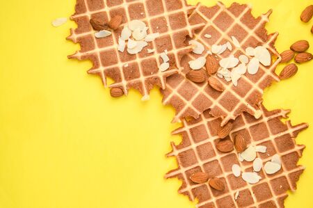 homemade waffles with almond nuts and almond flakes on the white and yellow background, copy spaceの写真素材