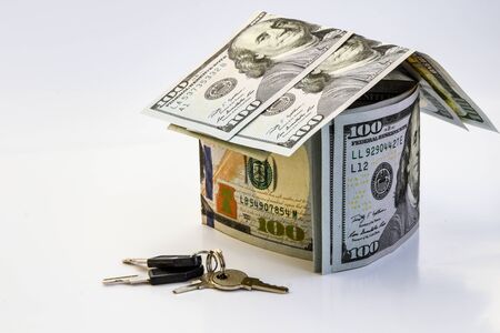 US dollar banknotes on display in the shape of a house on the white background, saving money for the house, copy spaceの写真素材