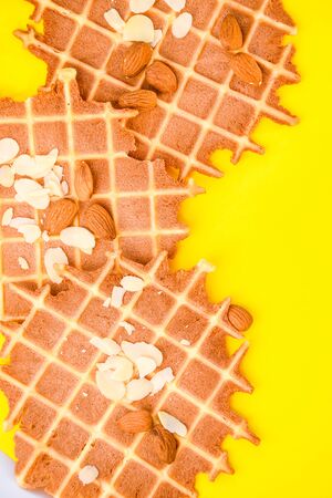 homemade waffles with almond nuts and almond flakes on the white and yellow background, copy spaceの写真素材