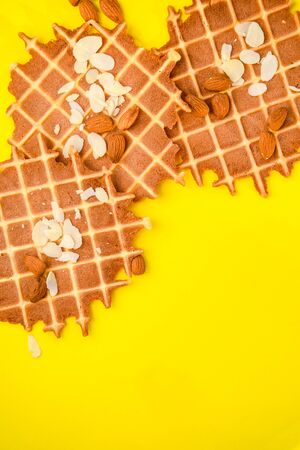 homemade waffles with almond nuts and almond flakes on the white and yellow background, copy spaceの写真素材