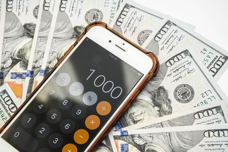 Close-up of Money and Calculator with One thousand on the Display ,It is a lot of One hundred dollars banknotes pile with calculatorの写真素材