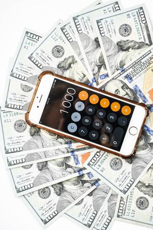 Close-up of Money and Calculator with One thousand on the Display ,It is a lot of One hundred dollars banknotes pile with calculatorの写真素材