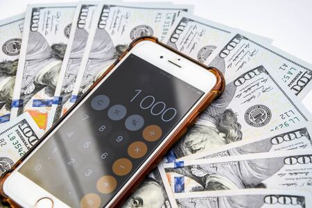 Close-up of Money and Calculator with One thousand on the Display ,It is a lot of One hundred dollars banknotes pile with calculatorの写真素材