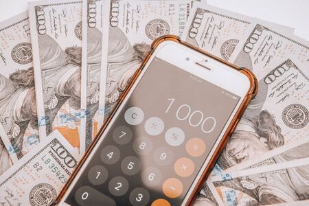 Close-up of Money and Calculator with One thousand on the Display ,It is a lot of One hundred dollars banknotes pile with calculatorの写真素材