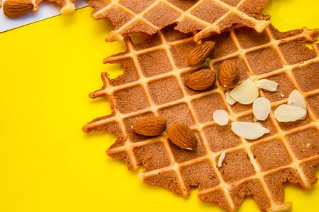 homemade waffles with almond nuts and almond flakes on the white and yellow background, copy spaceの写真素材