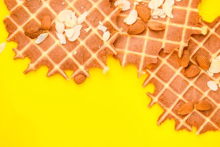 homemade waffles with almond nuts and almond flakes on the white and yellow background, copy spaceの写真素材