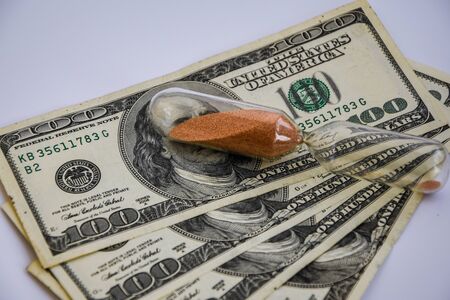 time is money, roll of american dollars, cash, sandglass on the white backround with place for text, wasting moneyの写真素材