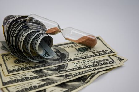 time is money, roll of american dollars, cash, sandglass on the white backround with place for text, wasting moneyの写真素材
