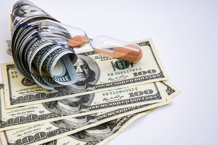 time is money, roll of american dollars, cash, sandglass on the white backround with place for text, wasting moneyの写真素材