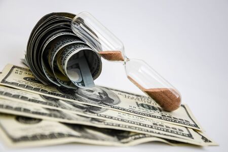 time is money, roll of american dollars, cash, sandglass on the white backround with place for text, wasting moneyの写真素材