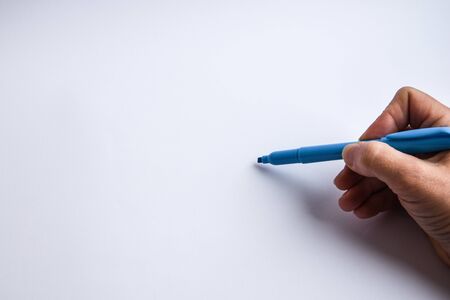 hand holding a pen and writing something on the white background, copy spaceの写真素材