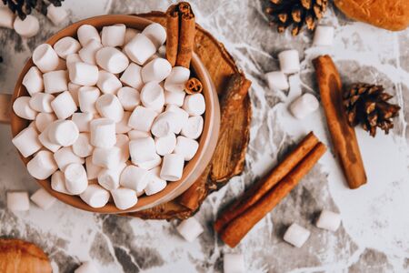a cup of Christmas New Year delicious hot chocolate and cocoa with marshmallows sprinkled with cocoa powder, cones and croissants, cinnamon on a gray table, selective focus Close up hot drink, top viewの写真素材
