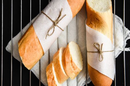 Sliced french baguette with crumbs on dark background, French homemade baguette bread. Wheat...