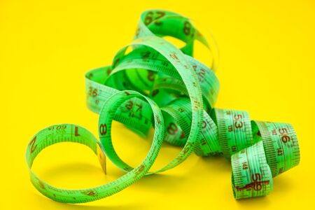 Close Up Tailor Measuring Tape on the yellow Background, Perspective view of spiral measuring tape, Close up of slimming conceptの写真素材