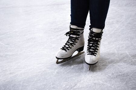 Female legs in white ice skates, Ice skater on the skating rink, Winter sport, close up of legs in skates on skating rink, Copy spaceの写真素材